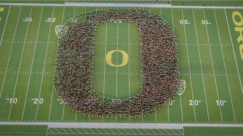 Overhead view of a group of students forming the "O" logo on the Autzen Stadium football field