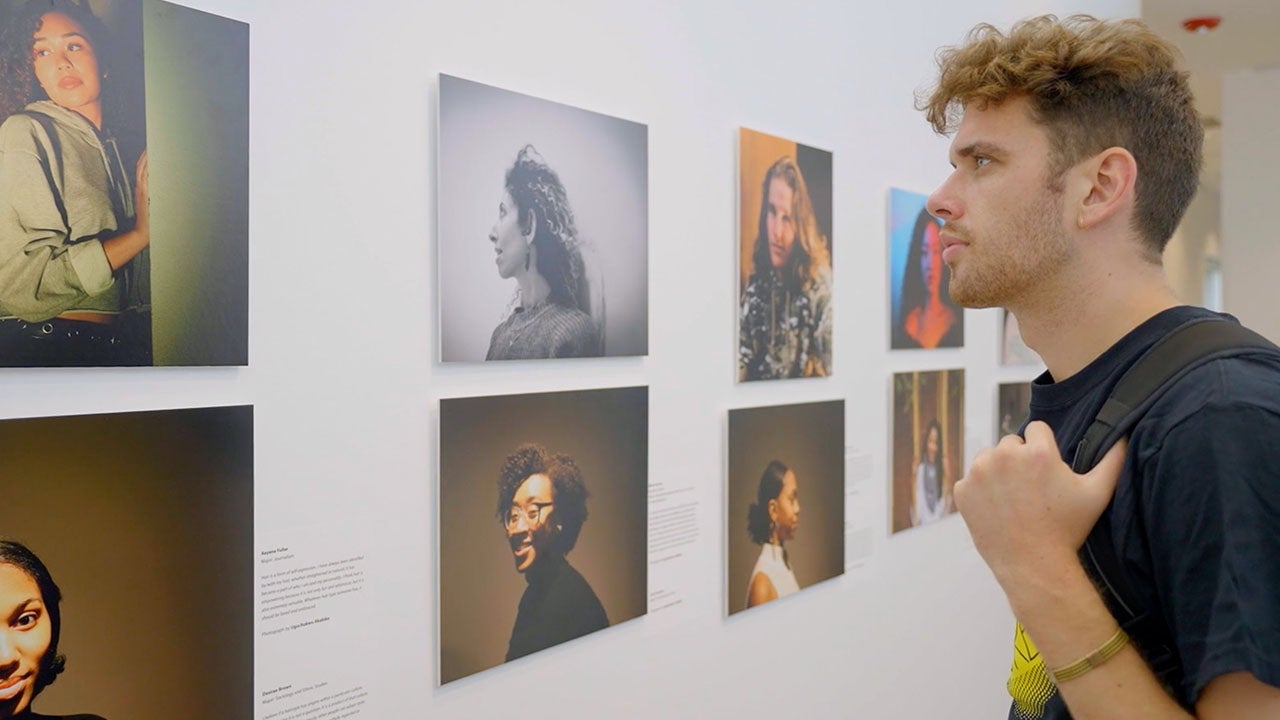 Student looking at photographs on wall.